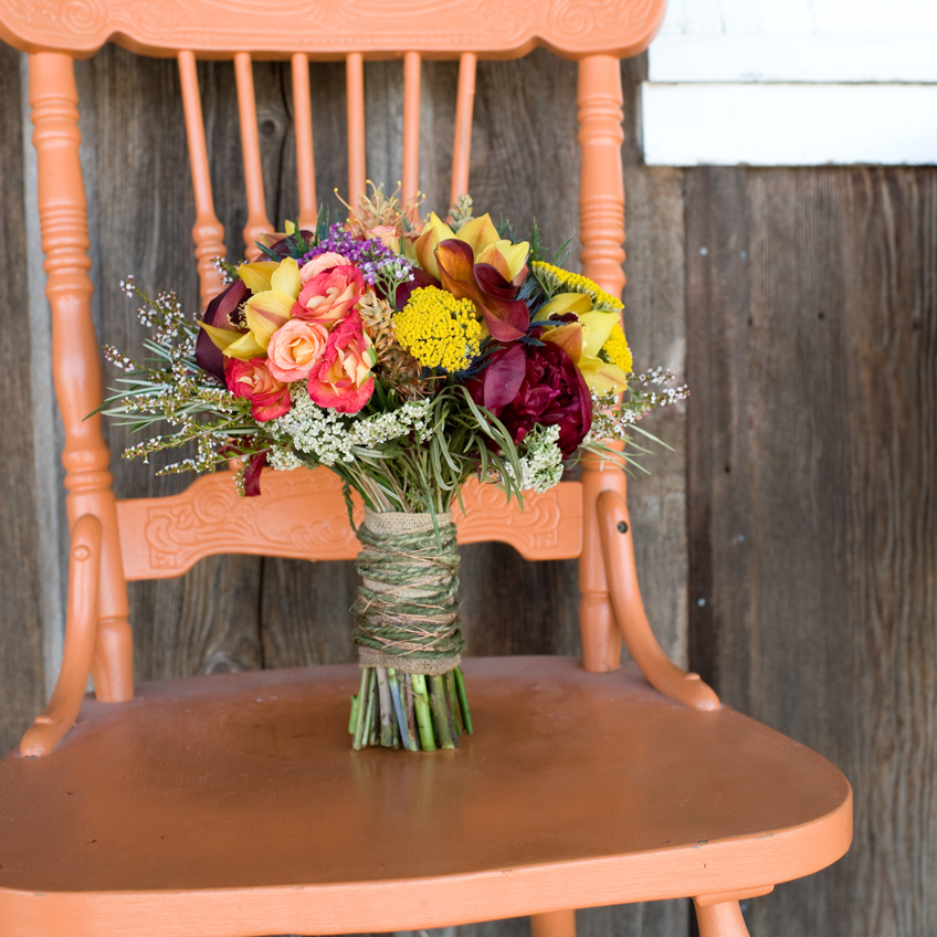 Vibrant seasonal bridal bouquet on a coral chair