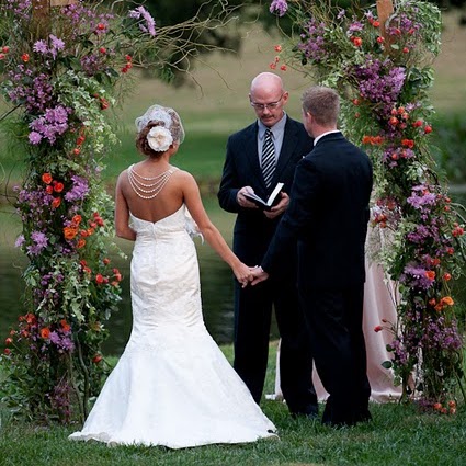 Lush floral ceremony arch framing a couple outdoors
